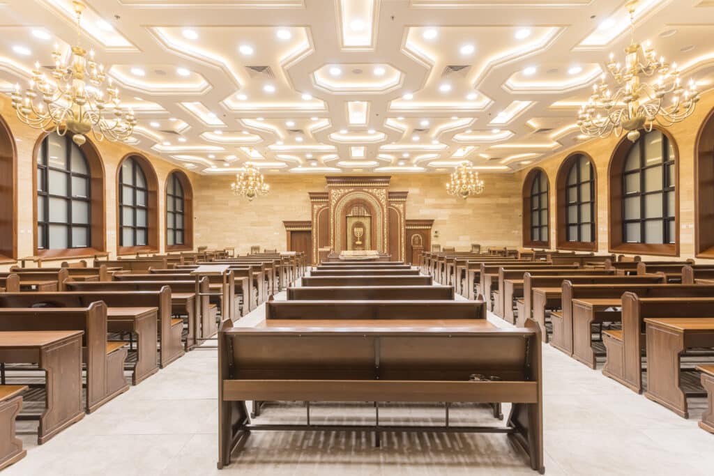 עבודות גבס אומנותיות בהיכל ישיבה הכוללות תקרה מעוצבת עם תאורה נסתרת וקרניזים."